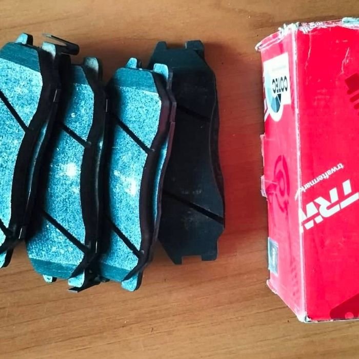 Quatre plaquettes de frein TRW posées à côté de leur boîte rouge